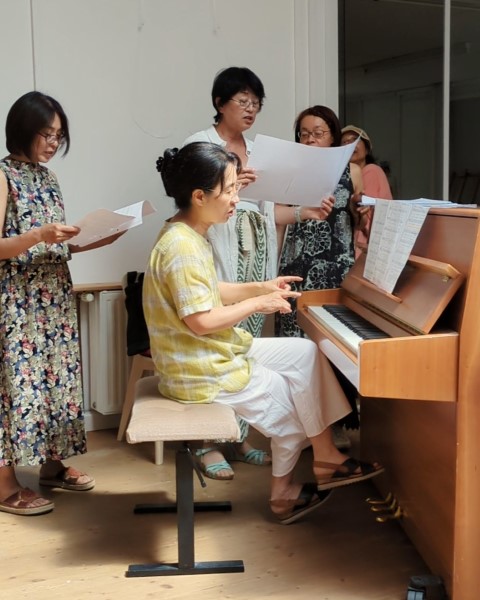 Menschen sind konzentriert um ein Klavier versammelt