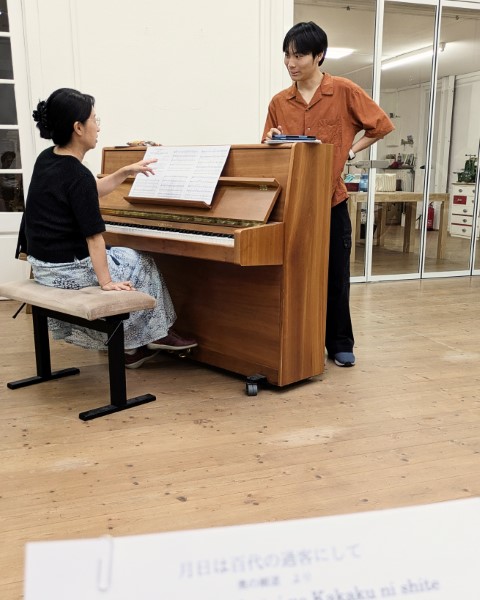 二人がピアノを前にして、ある楽曲について話し合っている。