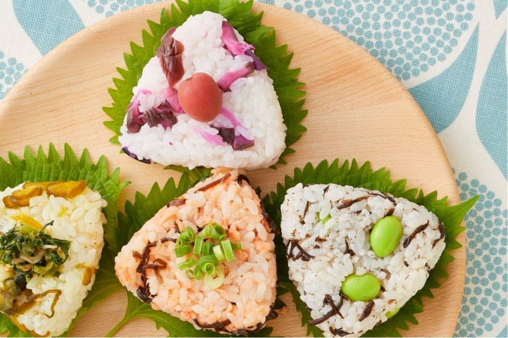 Vier Onigiri mit unterschiedlichen Füllungen auf einem Teller